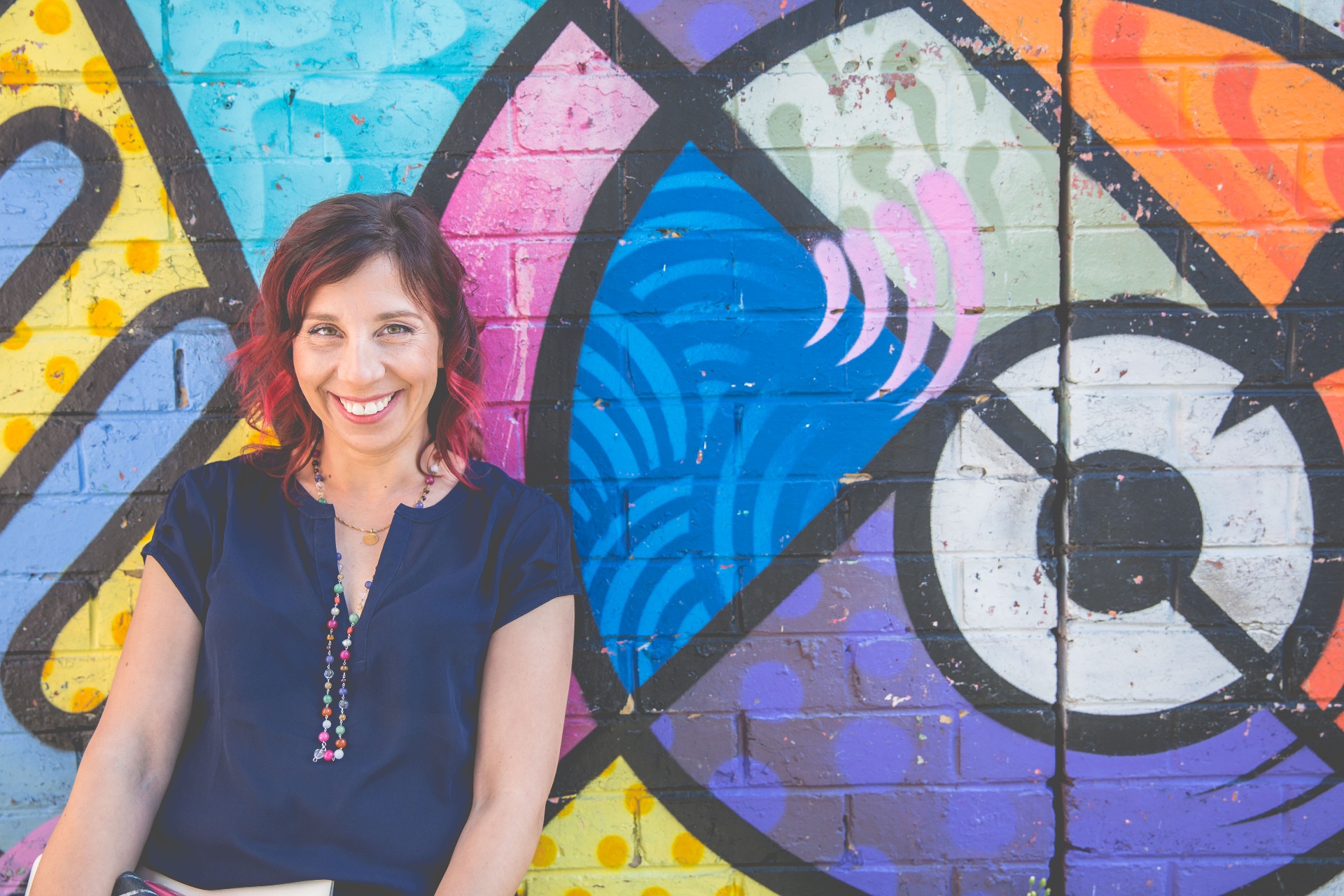Nathalie Martinek smiling in front of a colourful mural